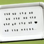 Kartonnen onderzetter met herhaling van 'YES NO YES NO', een hartje en 'maybe' – symboliseert de vraag: ben je klaar om te daten na een relatiebreuk of nog niet?