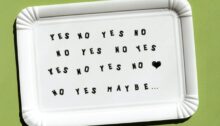 Kartonnen onderzetter met herhaling van 'YES NO YES NO', een hartje en 'maybe' – symboliseert de vraag: ben je klaar om te daten na een relatiebreuk of nog niet?